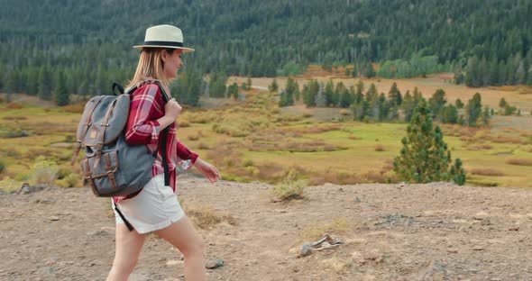 Woman Is Hiking By the Autumn Nature with Green Pine Trees on Background