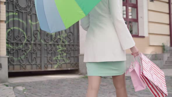 Side View of Unrecognizable Confident Woman Walking Along City Street with Shopping Bags. Elegant