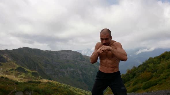 an Unshaven Man with a Bare Muscular Torso is Boxing in the Mountains