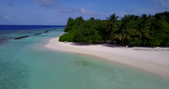 Wide overhead island view of a white sandy paradise beach and aqua blue water background in vibrant 