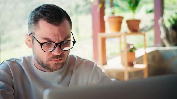 A Young Man Wearing Glasses Looking to the Laptop Screen