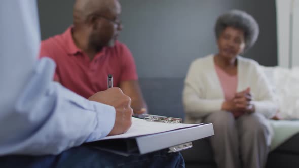 Mixed race senior male counsellor with clipboard advising to group of diverse senior friends