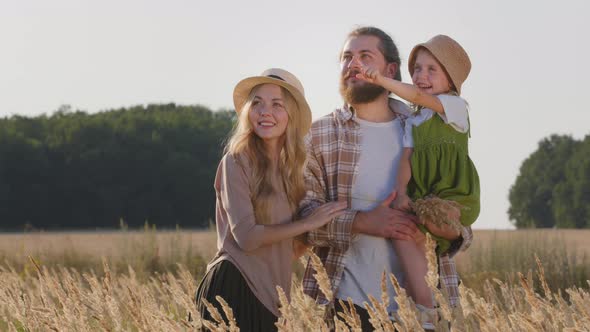 Happy Caucasian Family Loving Parents with Little Daughter Child Standing in Wheat Field in Nature