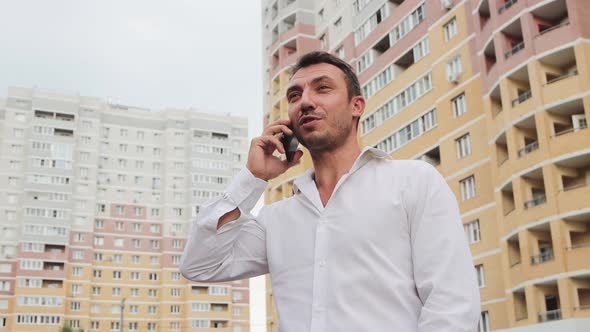 A Businessman in a White Shirt Speaks on the Phone with a Smile