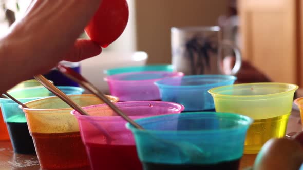 Easter eggs being dipped into colorful dye to prepare for Sunday.