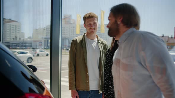 The Manager Shows a Young Couple a Car at a Dealership