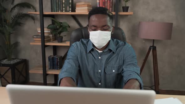 Confident Young African Businessman in Face Mask Office Workplace. Remote Chatting Colleague