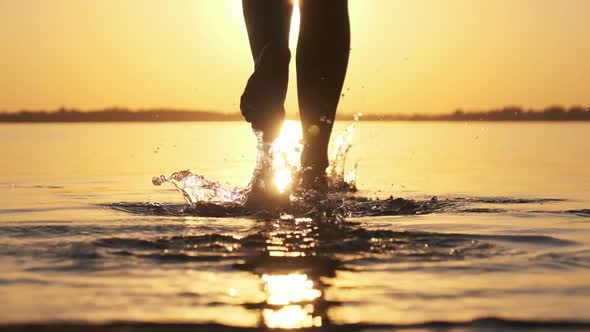 Woman Runs Into Shallow Water at Golden Sunset on the Beach. Slow Motion 240 Fps
