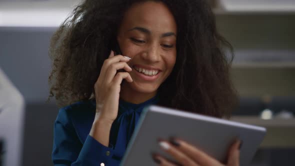 Smiling Woman Talking Phone Looking Tablet Pad in Office