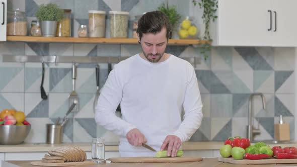 Healthy Young Man Cutting Vegetables in Kitchen