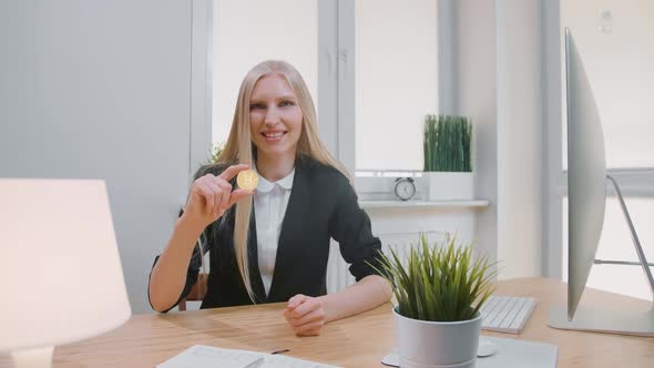 Happy Female with Bitcoin Showing Thumbs Up. Smiling Cheerful Blond Woman in Office Suit Sitting at
