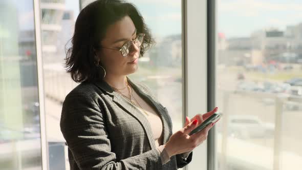 Business woman using a mobile phone, texting, typing text messages, checking email