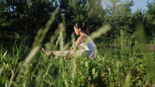 Woman Yogi on a Gym Mat. Camera Movement Among Grass