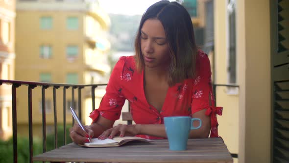 A woman writing in a journal diary traveling in a luxury resort town in Italy, Europe