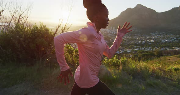 African american woman exercising outdoors running in country side during sunset
