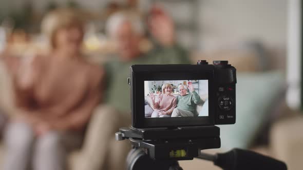 Digital Camera Filming Positive Elderly Couple at Home