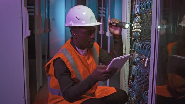 Black Male Technician Checking Switches in Data Center