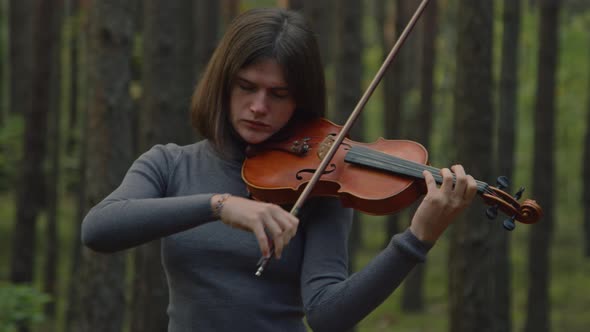 Woman Musician Is Playing Violin Among Trees