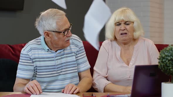 Stressed Senior Couple Discuss Unpaid Bank Debt Holding Bills, Doing Paperwork, Planning Budget