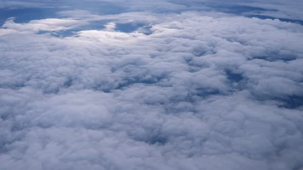 Flying Over the Layer of Clouds and Looking on Landscape Through the Clouds