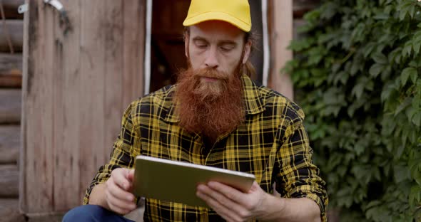 A Man with a Red Beard Takes Notes on a Laptop