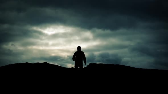 Man Approaches Over Hill On Dramatic Sky Silhouette