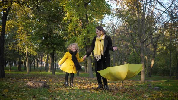 Great Family, Handsome Mother with a Lovely Little Kid, Playing in Autumn Leaves with an Umbrella