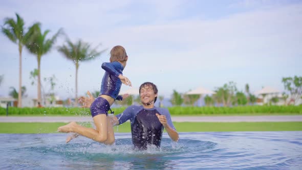 Slowmotion Shot of a Father and Son That Are Having Fun in a Swimming Pool