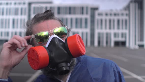 Bearded man with sunglasses, respirator and protective suit looks to sun 
