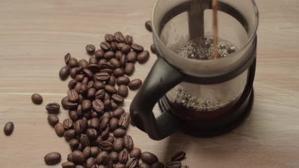 Pouring fresh coffee into a pot with coffee beans background