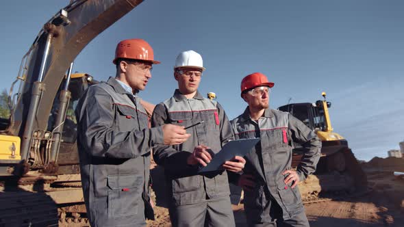 Team of Professional Male Engineering Worker in Uniform Discussing Working Plan at Construction Site