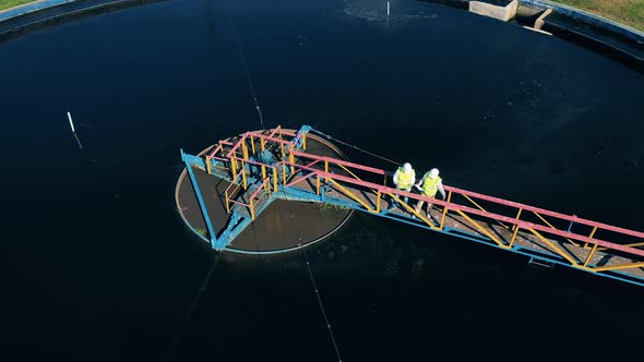 Male Specialists Observing a Water Reservoir at a Cleaning Facility