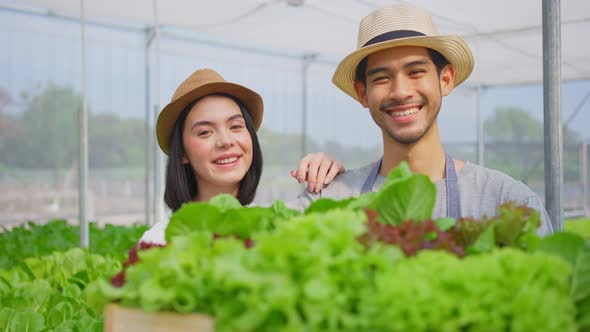 Portrait of Asian couple farmers owner working in vegetables hydroponic farm and looking at camera