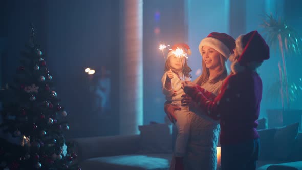 Mother and Her Daughters Using Sparklers Near Christmas Tree