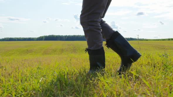 Farmer Feet Wearing Rubber Boots Walking in Mown Field