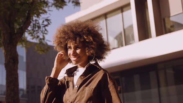 Woman With Afro Lost In Music From Her Headphones In City