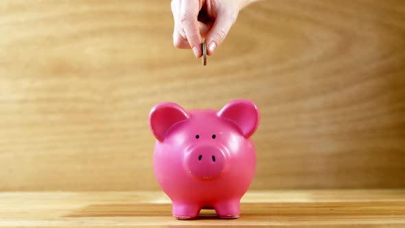 Hand dropping coin into piggy bank