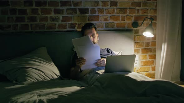 Video of man lying in bed during working at night. Shot with RED helium camera in 8K.