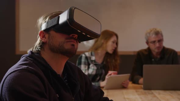 Man wearing VR headset with colleagues working in creative office