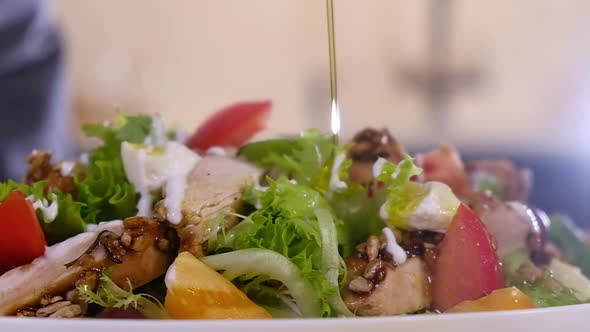 chef pours olive oil on salad of fresh vegetables. Cooking salad in kitchen home