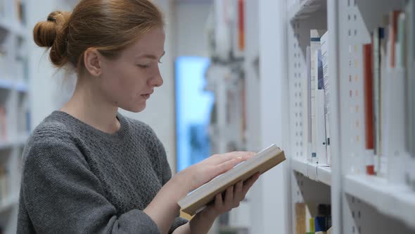 Redhead Woman Finding and Taking Book in Library