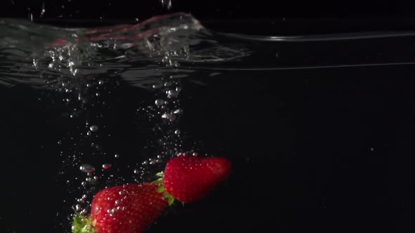 Three Juice Strawberryes Splashing Into Water in Slowmotion