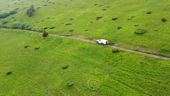 White Suv Rides On A Mountainous Terrain On A Dirt Road. Aerial View.  50