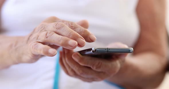 Hands of an Elderly Woman on the Screen of a Smartphone