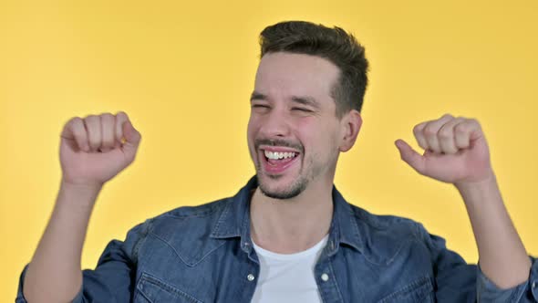 Portrait of Cheerful Young Man Dancing To Music, Yellow Background