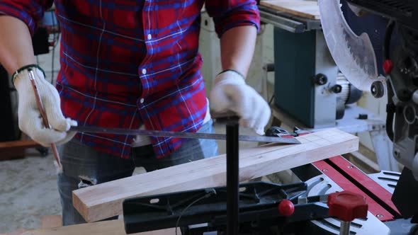 Close-up of Carpenter mark the pencil line on wood before cutting on cutting machine