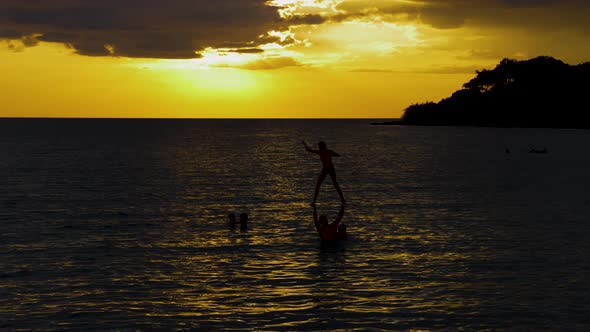 Silhouettes of family playing in the sea at dusk.