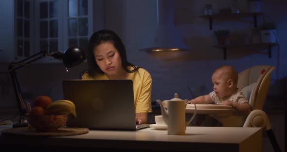 Young Mother with Baby Working on Laptop