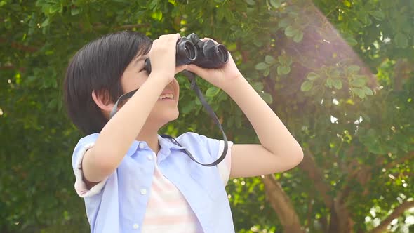 Cute Asian Child Using Binocular On Summer Day