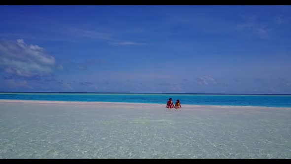 Family of two suntan on marine bay beach wildlife by blue green ocean with white sandy background of